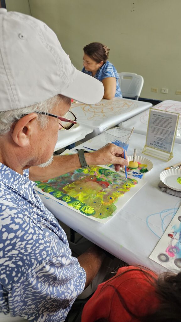 Participante aplica puntos de color a su obra durante una experiencia creativa de MOSAIK